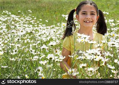 Girl (7-9) holding flowers in meadow, portrait