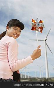 Girl (7-9) holding windmill, sitting on fathers shoulders at wind farm, portrait