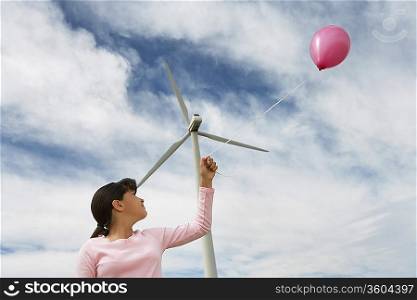 Girl (7-9) playing with balloon at wind farm