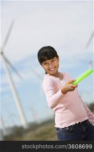 Girl (7-9) throwing disc at wind farm, portrait