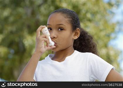 Girl (7-9) using inhaler, outdoors