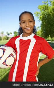 Girl (7-9 years) soccer player holding ball under arm, portrait