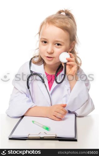 Girl 7 years with stethoscope in the doctor's suit playing, photo on the white background