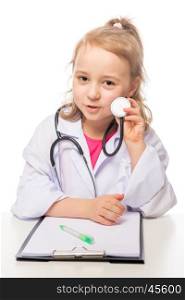 Girl 7 years with stethoscope in the doctor's suit playing, photo on the white background