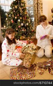 Girl and a teenage girl opening Christmas presents