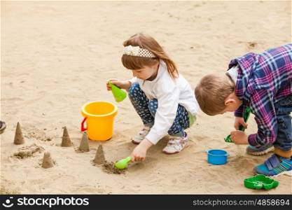 Girl and boy building figures with sand in a sandbox. Children playing in a sandbox