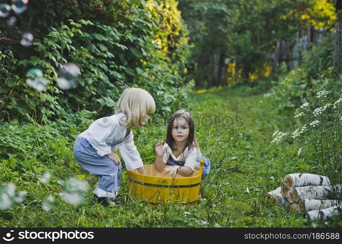 Girl and boy playing outdoors with soap bubbles.. Children playing with soap bubbles 4736.