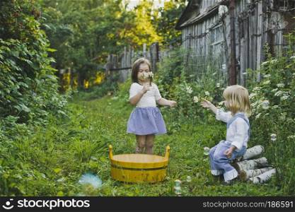 Girl and boy playing outdoors with soap bubbles.. Children playing with soap bubbles 4748.
