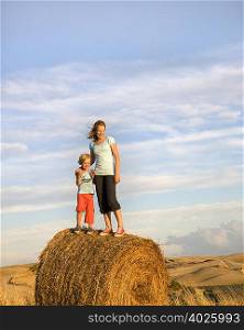 girl and boy standing on hay bale