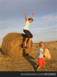 girl and boy with hay bale