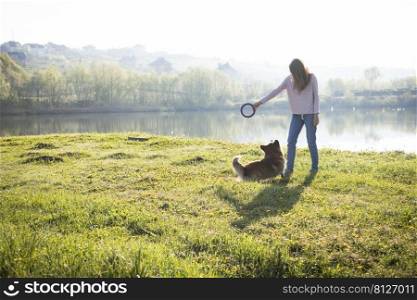 girl and dog walking on the lake. beautiful corgi dog play with his toy 
