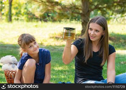 Girl and girl have fun at a teapot at a picnic