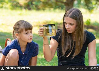 Girl and girl with interest look at a teapot at a picnic