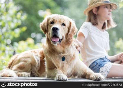 Girl and Golden retriever dog sitting on pier