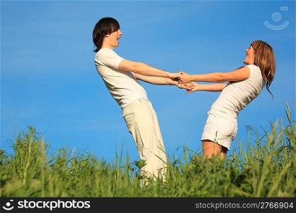 girl and guy stand on grass having joined hands