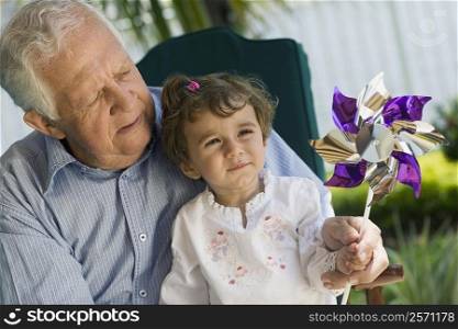Girl and her grandfather playing with a pinwheel