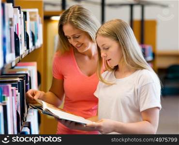 Girl and her mother in library choosing books. Girl and her mother in library