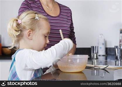 Girl and mother cooking together in kitchen