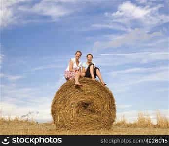 girl and woman sitting on hay bale