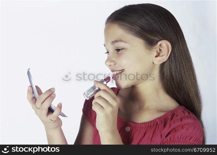 Girl applying lipstick holding a mirror