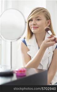 Girl applying makeup in front of mirror at home