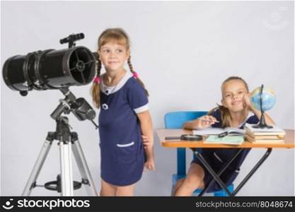 Girl astronomer looks at the sky, the other girl sitting happily at the table