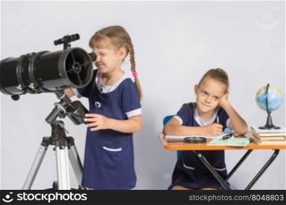 Girl astronomer looks through the eyepiece of the telescope, the other girl thinking waiting for the results of observations