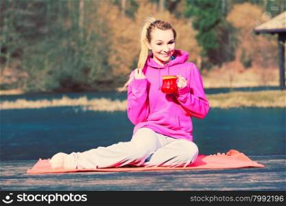 Girl at park holding mug.. Young pretty girl at park holding mug with hot tea. Woman care about health sitting on fresh air.