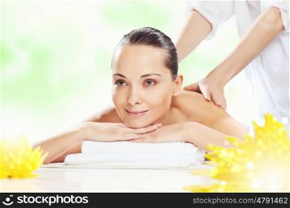 Girl at spa massage. Young pretty woman with clear skin at spa salon getting massage