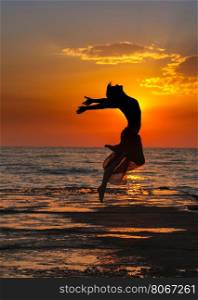 girl at sunset. Girl jumping on a background of sea sunset