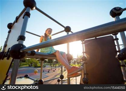 girl at the large beautiful playground in the park. Summer and active lifestyle