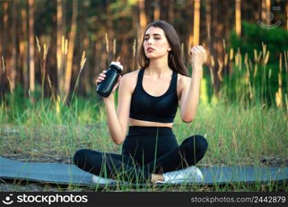 Girl athlete with sits in the park with a bottle of water. Girl athlete with sits in park with bottle of water