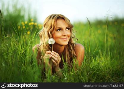 girl blow on dandelion on green field