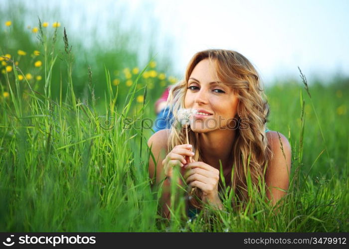 girl blow on dandelion on green field