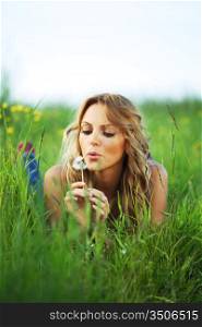 girl blow on dandelion on green field