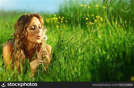 girl blow on dandelion on green field. i wish