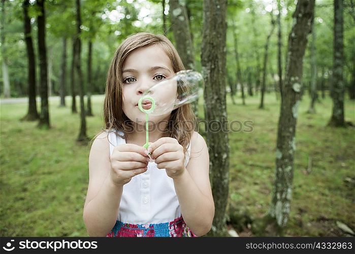 Girl blowing bubbles in forest