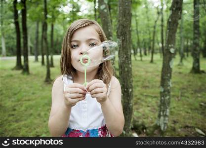 Girl blowing bubbles in forest