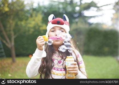 Girl blowing bubbles in garden