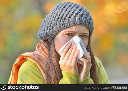 girl blowing nose in autumn background