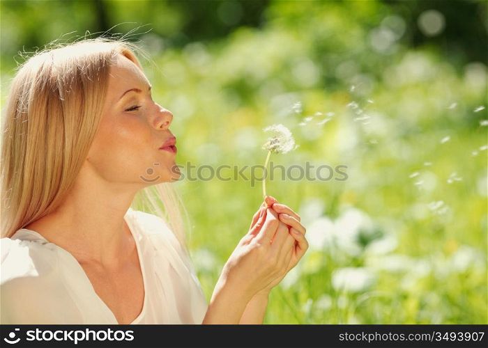 girl blowing on a dandelion lying on the grass