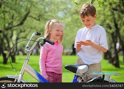 girl, boy and bicycle in park in spring