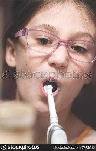 Girl brushing her teeth with an electric brush