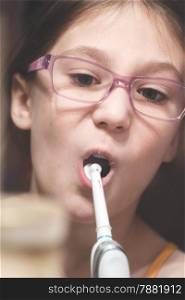 Girl brushing her teeth with an electric brush