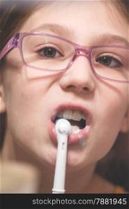 Girl brushing her teeth with an electric brush