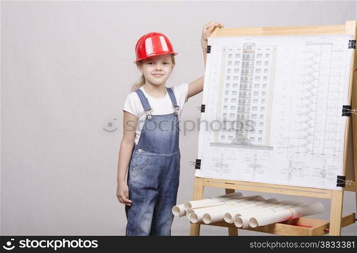 Girl Builder, architect, stands at the blackboard with the drawing of the building