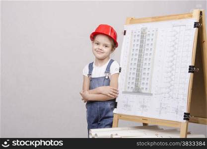 Girl Builder, architect, stands at the blackboard with the drawing of the building