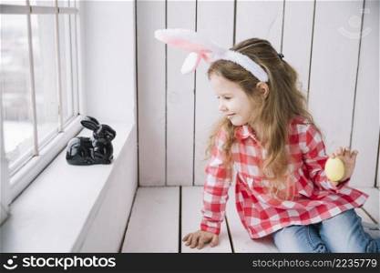 girl bunny ears holding yellow easter egg