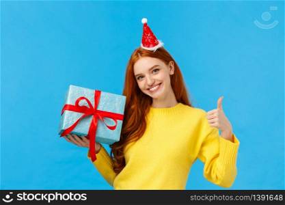 Girl can wrap your gift easily. Pleased and assertive pretty redhead female shop assistant help out customer, showing thumb-up, all done or good gesture, smiling holding box of present.. Girl can wrap your gift easily. Pleased and assertive pretty redhead female shop assistant help out customer, showing thumb-up, all done or good gesture, smiling holding box of present