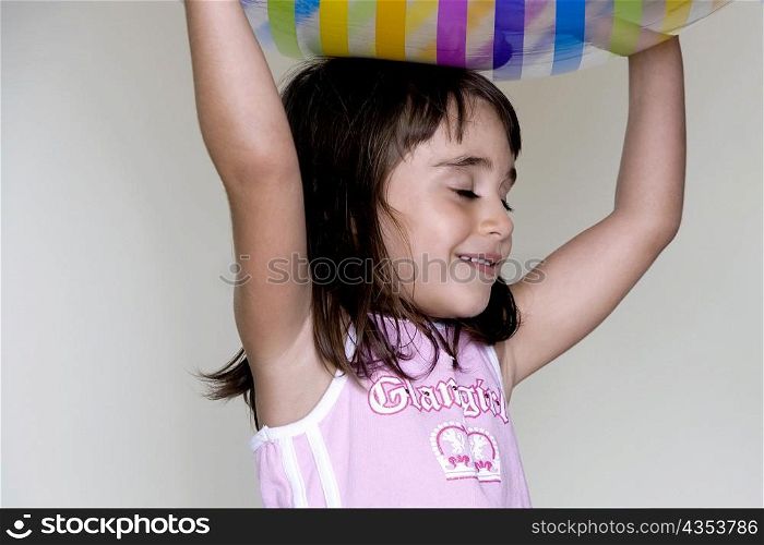 Girl carrying an inflatable ball over her head